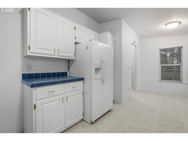 a kitchen with white cabinets and refrigerator