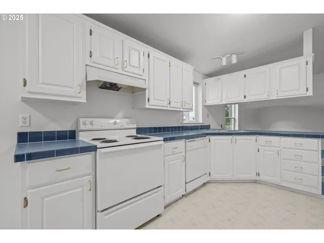 a kitchen with granite countertop white cabinets and white appliances