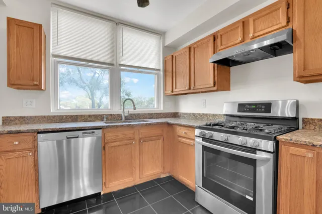 a kitchen with granite countertop wooden cabinets stainless steel appliances and a window