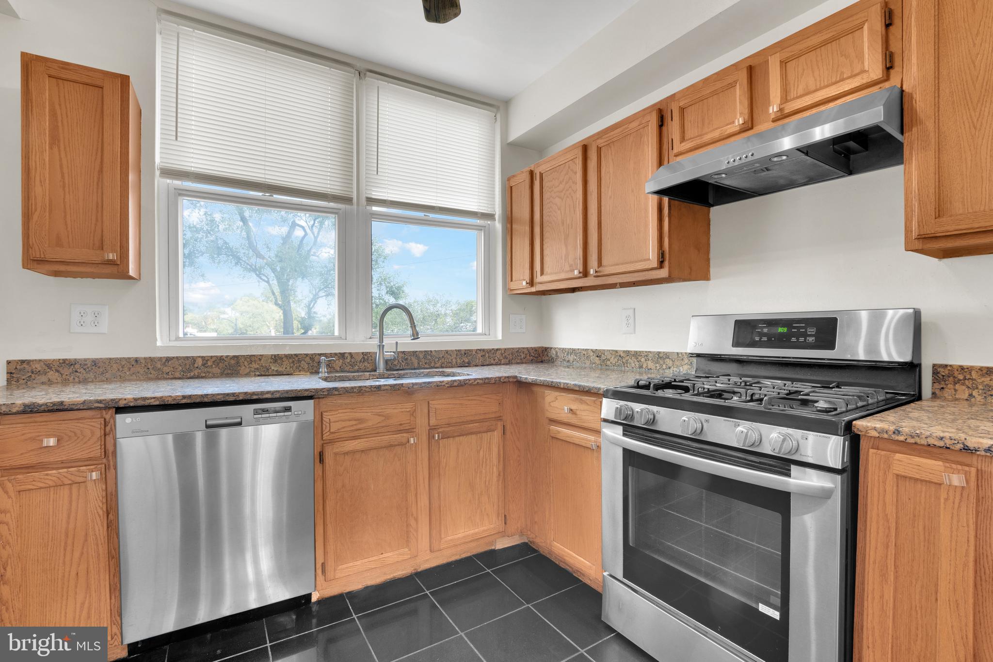 5731 9th Street Northwest Washington, DC 20011 - Photo 14 of 36 a kitchen with granite countertop wooden cabinets stainless steel appliances and a window