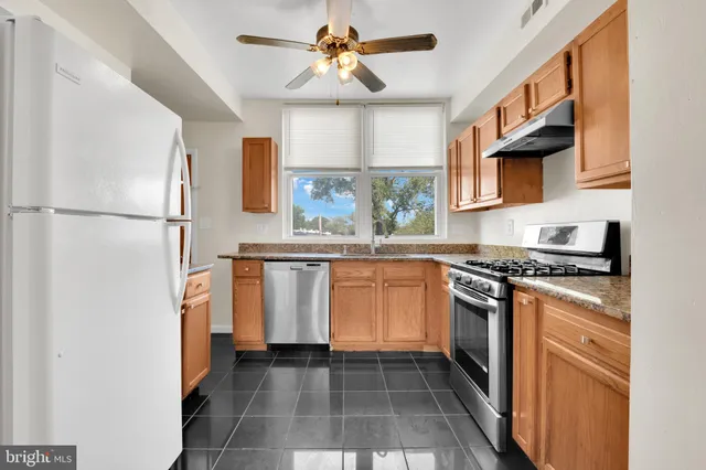 a kitchen with white cabinets a sink a stove and a refrigerator