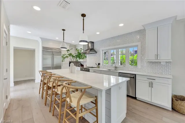 a kitchen with stainless steel appliances granite countertop a sink a stove a refrigerator and island with wooden floor