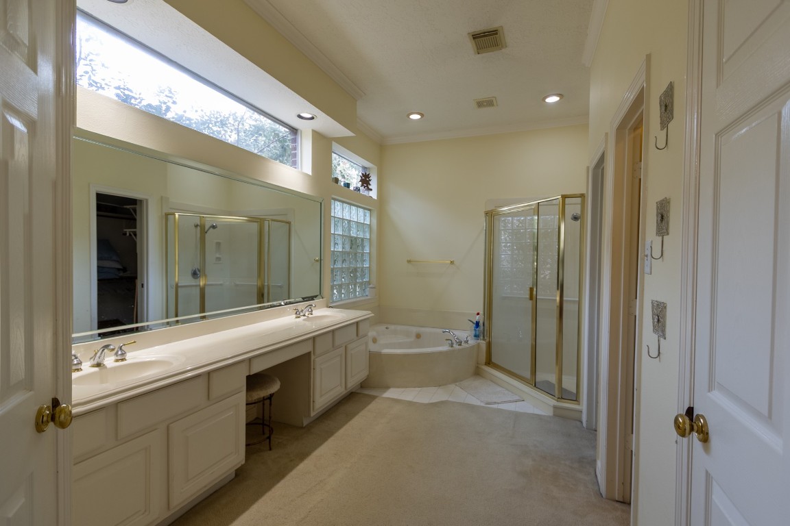 5718 Oakmoss Trail Spring, TX 77379 - Photo 29 of 50 Luxurious primary bath with a spa feel, featuring a vanity with seating, separate shower and tub, two walk-in closets, and abundant natural light.