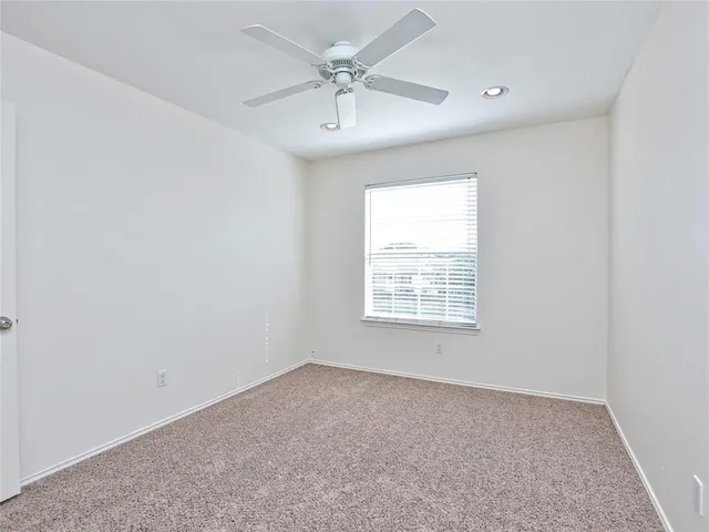 an empty room with a chandelier fan and windows