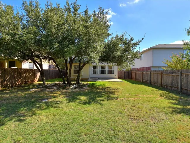 a view of a yard in front of a house with large tree