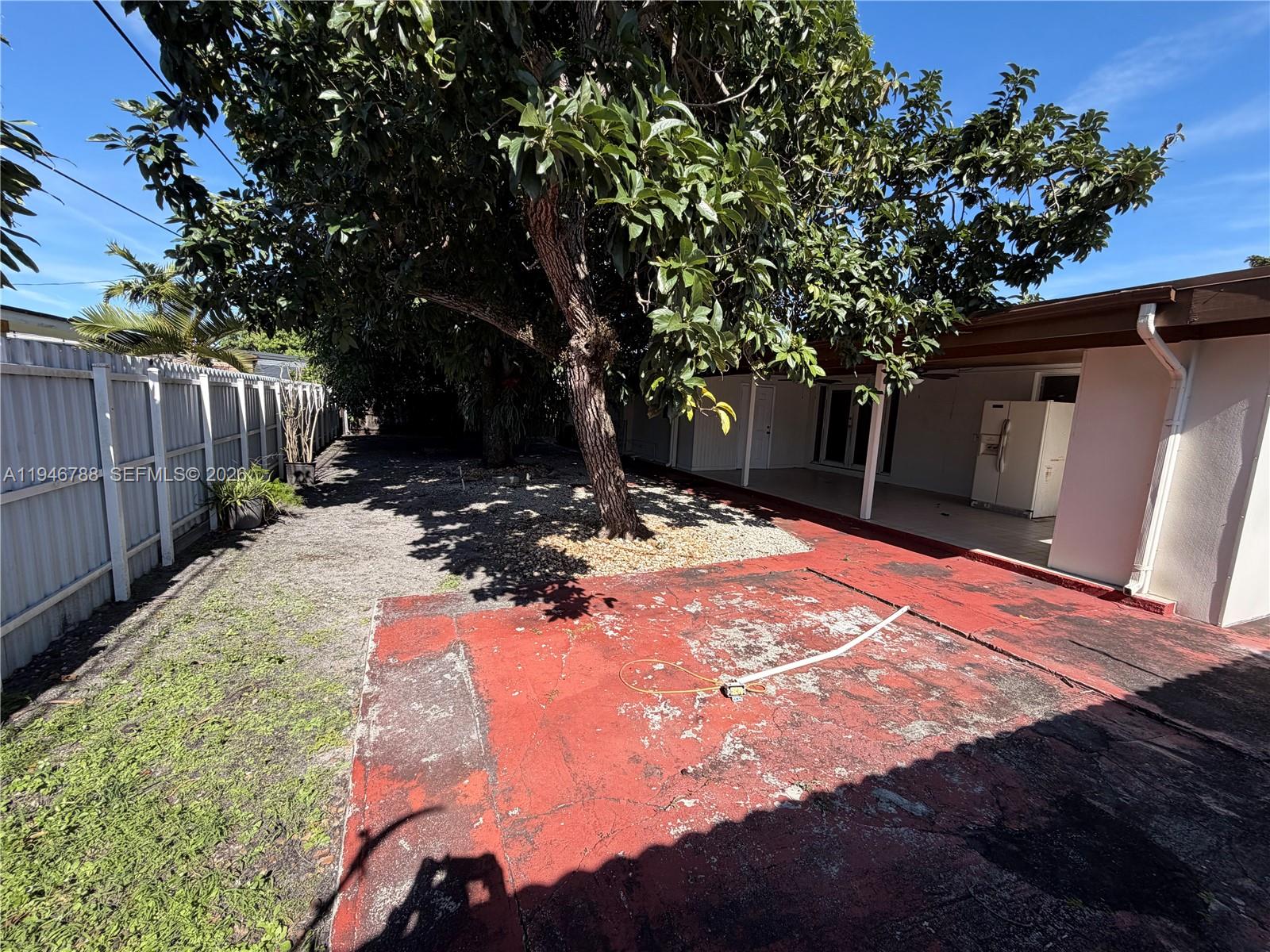 6090 West 5th Lane Hialeah, FL 33012 - Photo 20 of 28 a view of a backyard with wooden fence and a large tree