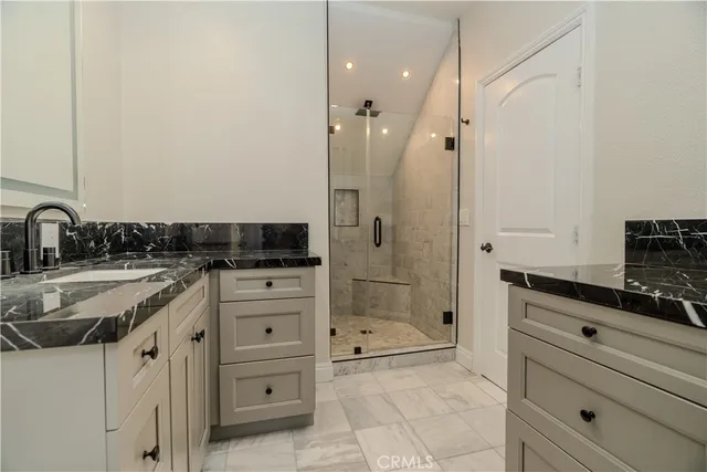 a bathroom with a granite countertop sink a mirror and a shower