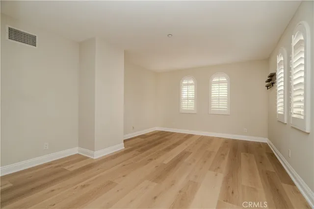 a view of an empty room with wooden floor and window