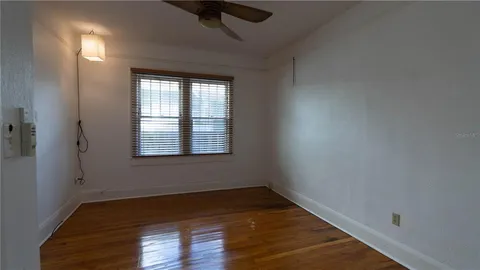 a view of an empty room with wooden floor and a window