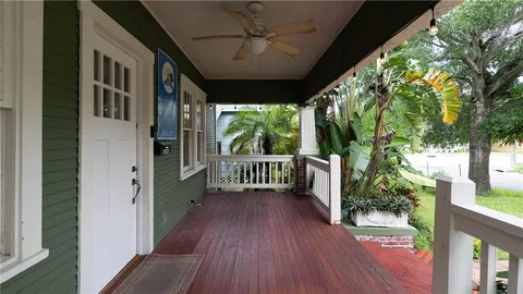 a view of a livingroom with a fireplace a ceiling fan and wooden floor