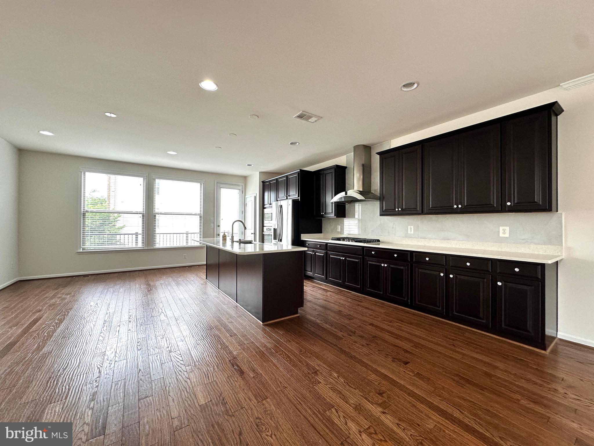23451 Epperson Square Brambleton, VA 20148 - Photo 12 of 42 a kitchen with stainless steel appliances granite countertop a stove a sink dishwasher a microwave oven with cabinets and wooden floor