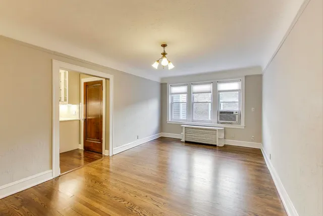 a dining room with wooden floor and a chandelier