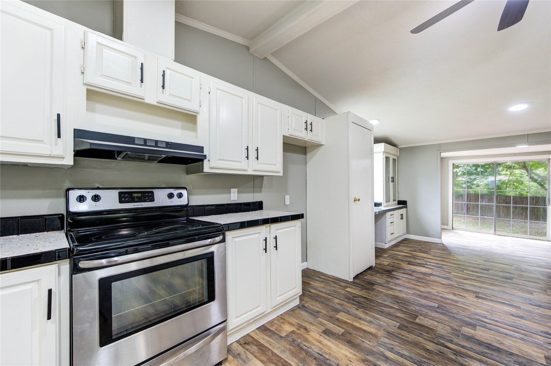 30226 Davis Street Magnolia, TX 77355 - Photo 23 of 50 Spacious kitchen with modern appliances, white cabinetry, and wooden flooring. It opens to a bright dining area with large windows overlooking the backyard.