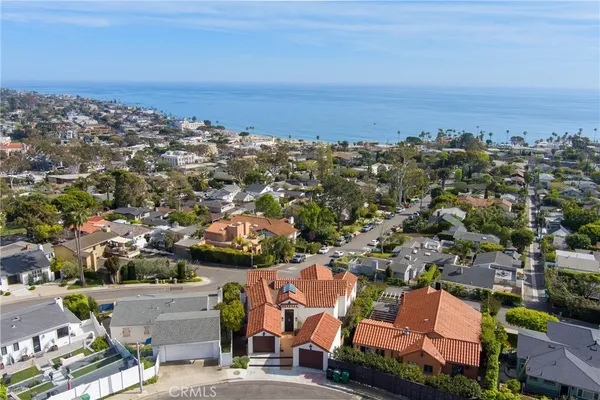 an aerial view of a city with lots of residential buildings and ocean view in back
