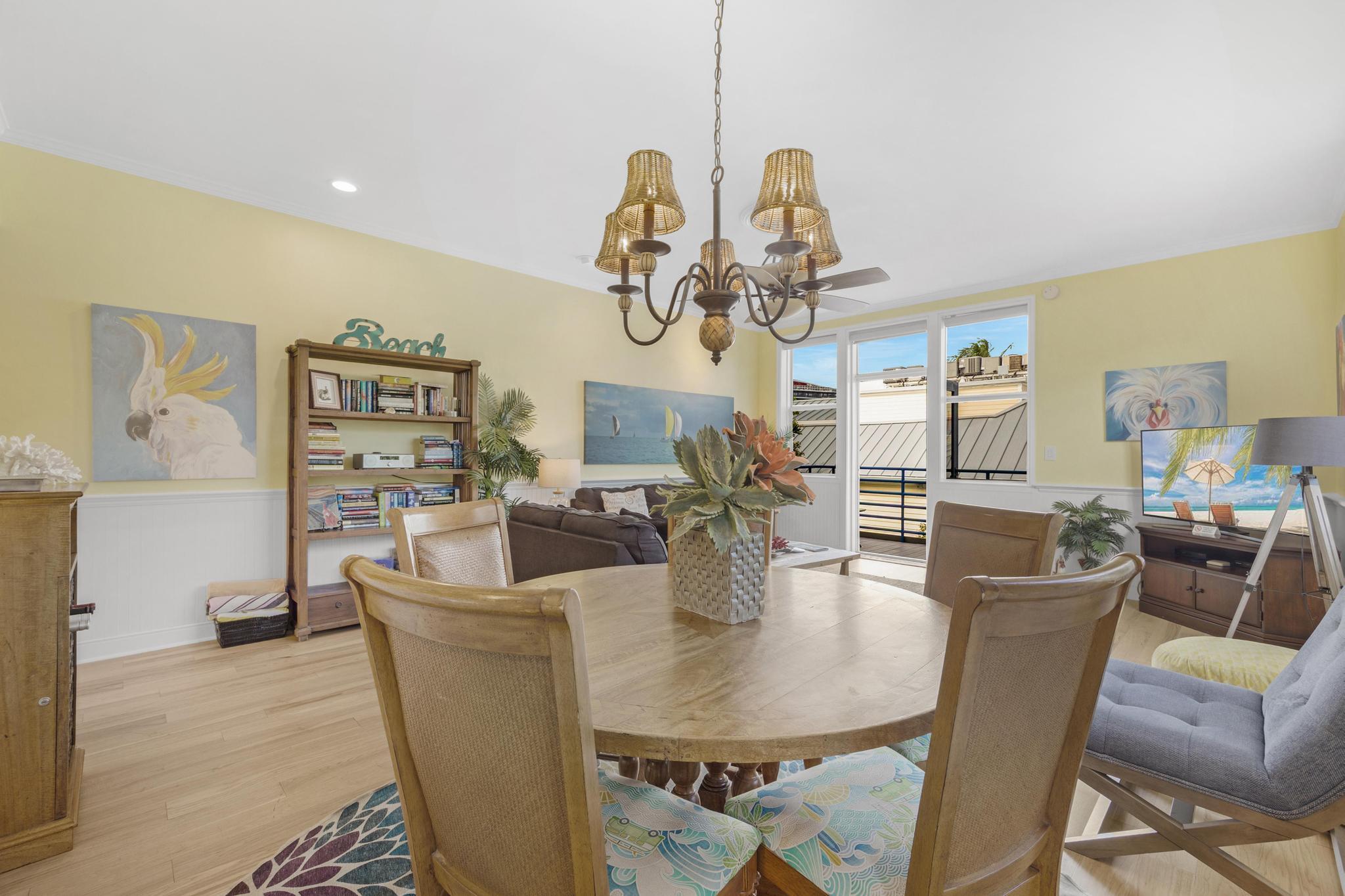 115 Front Street, Unit 301 Key West, FL 33040 - Photo 19 of 52 a dining room with wooden floor a chandelier a glass table and chairs