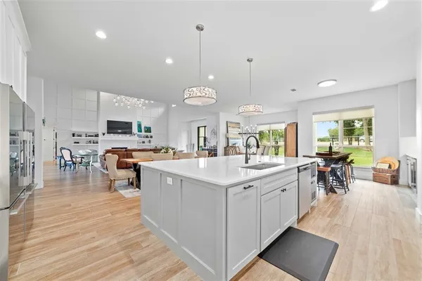 a large kitchen with stainless steel appliances a large center island wooden floor and cabinets