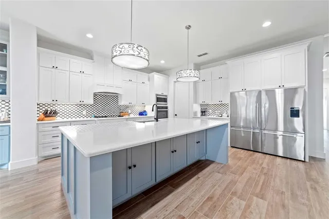 a large kitchen with stainless steel appliances kitchen island granite countertop a sink and dishwasher a stove top oven with white cabinets