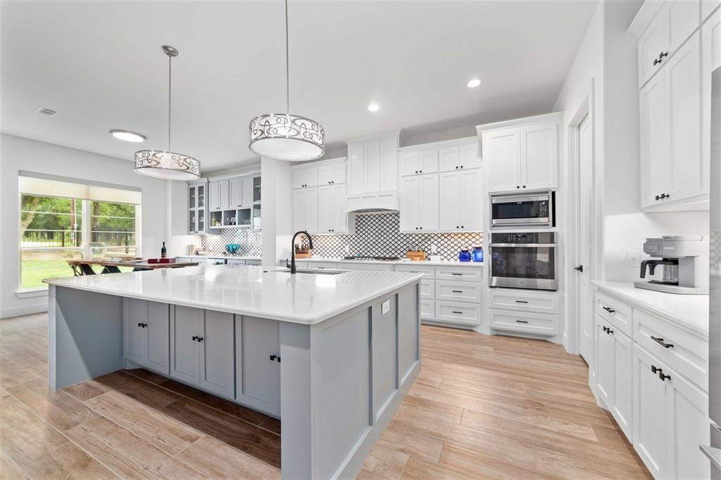 582 Oak Point Drive May, TX 76857 - Photo 10 of 37 a large kitchen with stainless steel appliances kitchen island granite countertop a sink and dishwasher a stove top oven with white cabinets