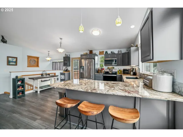 a kitchen with stainless steel appliances granite countertop a sink counter space and chairs