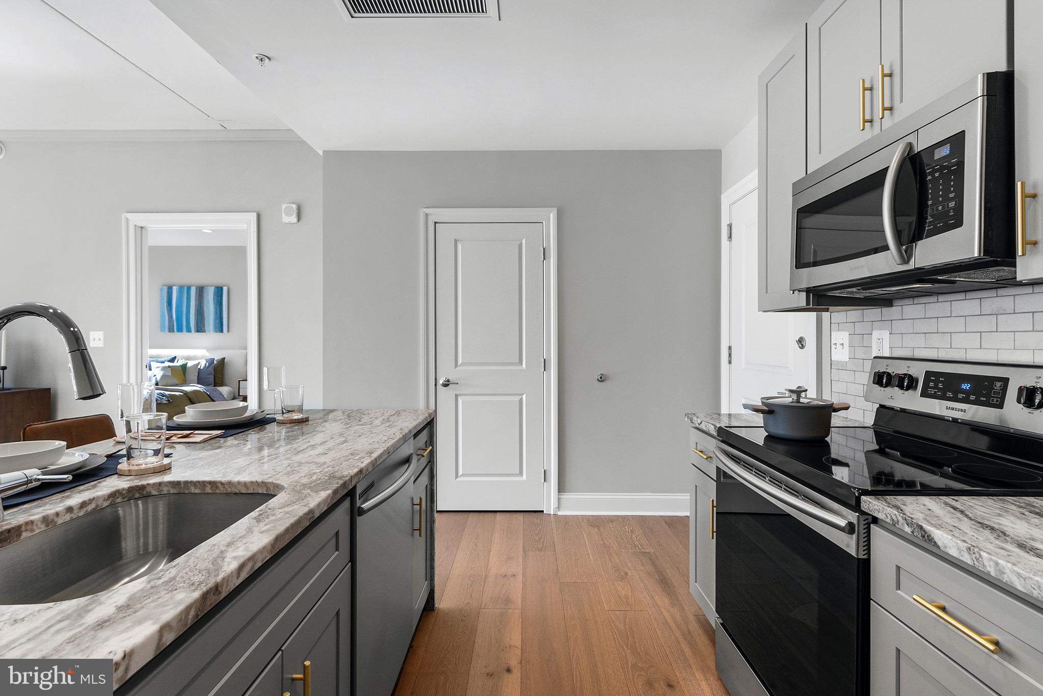 a kitchen with granite countertop a sink dishwasher stove and microwave with wooden floor