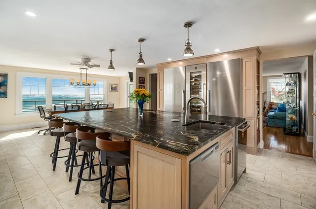 a kitchen with stainless steel appliances granite countertop a stove top oven a sink a dining table and chairs with wooden floor