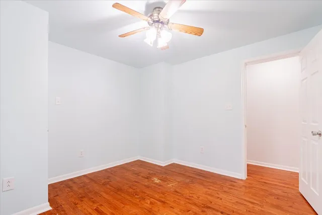 a view of a room with wooden floor and a ceiling fan