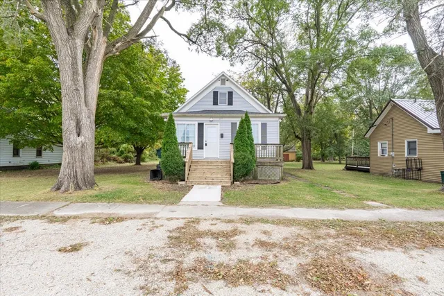 a front view of a house with a yard and large trees