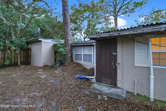 a view of a small house with a yard and large trees