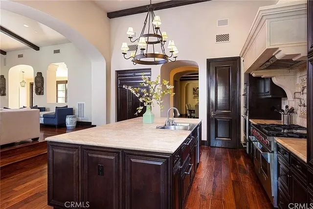 a kitchen with stainless steel appliances kitchen island granite countertop a refrigerator a stove and a sink with wooden floor