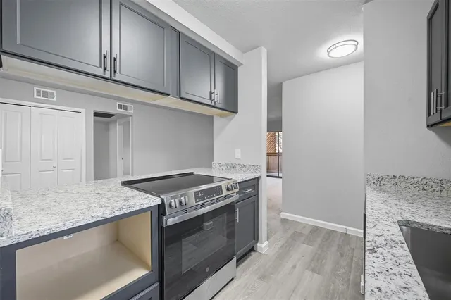 a kitchen with granite countertop cabinets stainless steel appliances and wooden floor