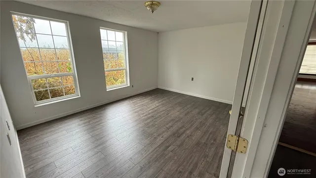 a view of an empty room with wooden floor and a window