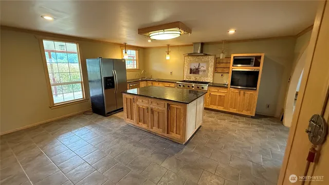 a kitchen with stainless steel appliances granite countertop a refrigerator and a stove top oven