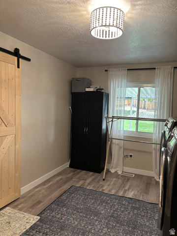 1324 West Raintree Drive, Unit 44 Price, UT 84501 - Photo 10 of 25 Light wood-finish barn door with black hardware, wood-finish flooring, and a decorative semi-flush mount ceiling light fixture