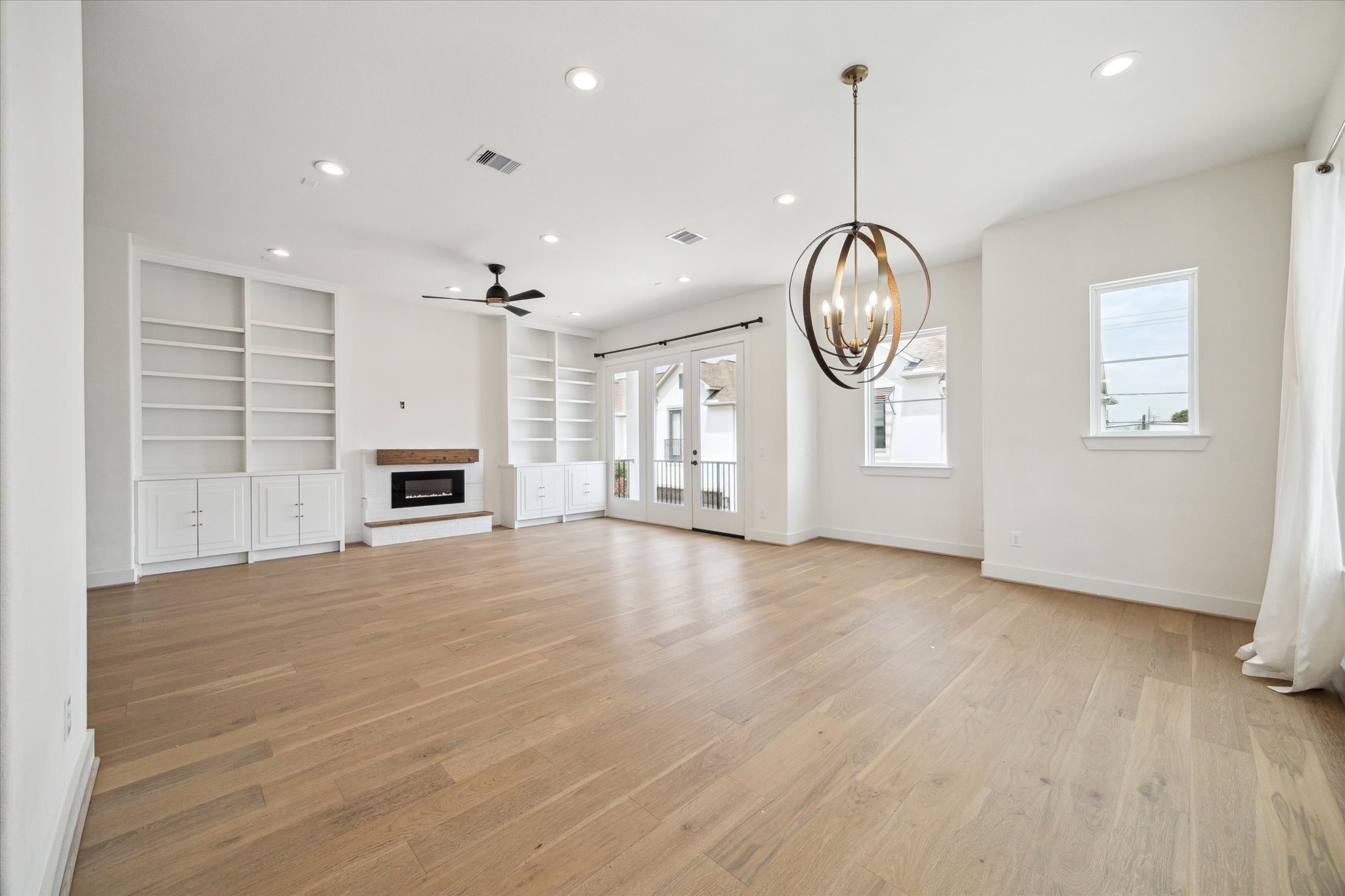 1747 Ojeman Spring Lane Houston, TX 77055 - Photo 3 of 22 an empty room with wooden floor cabinet and windows