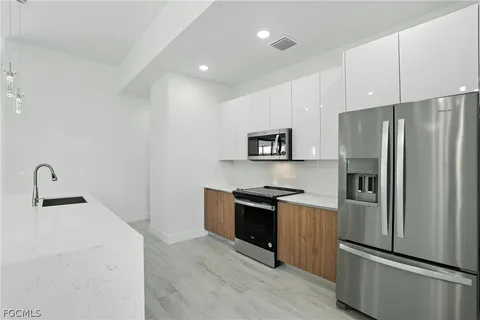 a kitchen with granite countertop a refrigerator stove and sink