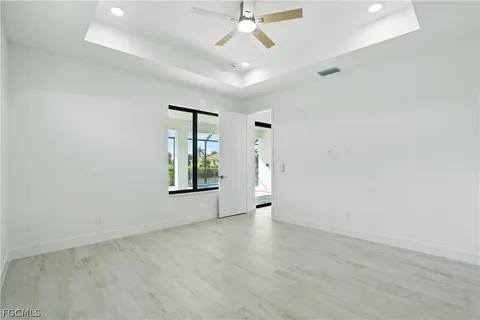 an empty room with windows and ceiling fan