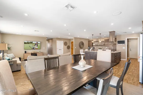 a living room with stainless steel appliances furniture a dining table and kitchen view