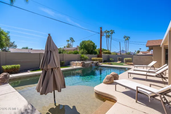 a view of a backyard with couches under an umbrella