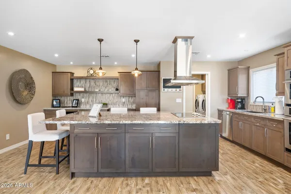 a kitchen with kitchen island granite countertop a sink cabinets and stainless steel appliances