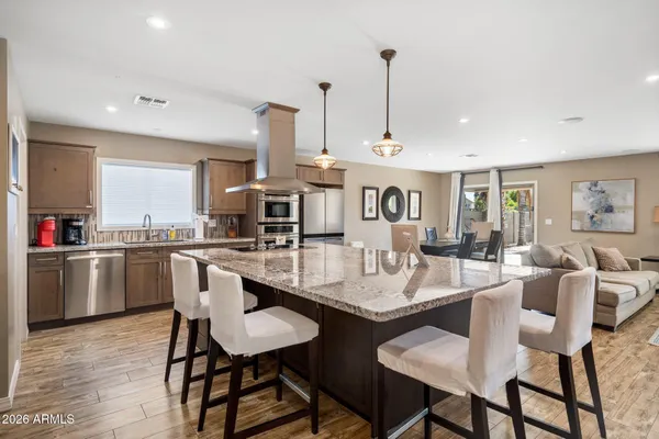 a dining room with stainless steel appliances kitchen island granite countertop a dining table chairs and view of living room