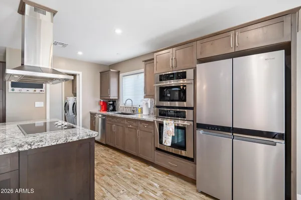 a kitchen with stainless steel appliances granite countertop a refrigerator a sink and white cabinets