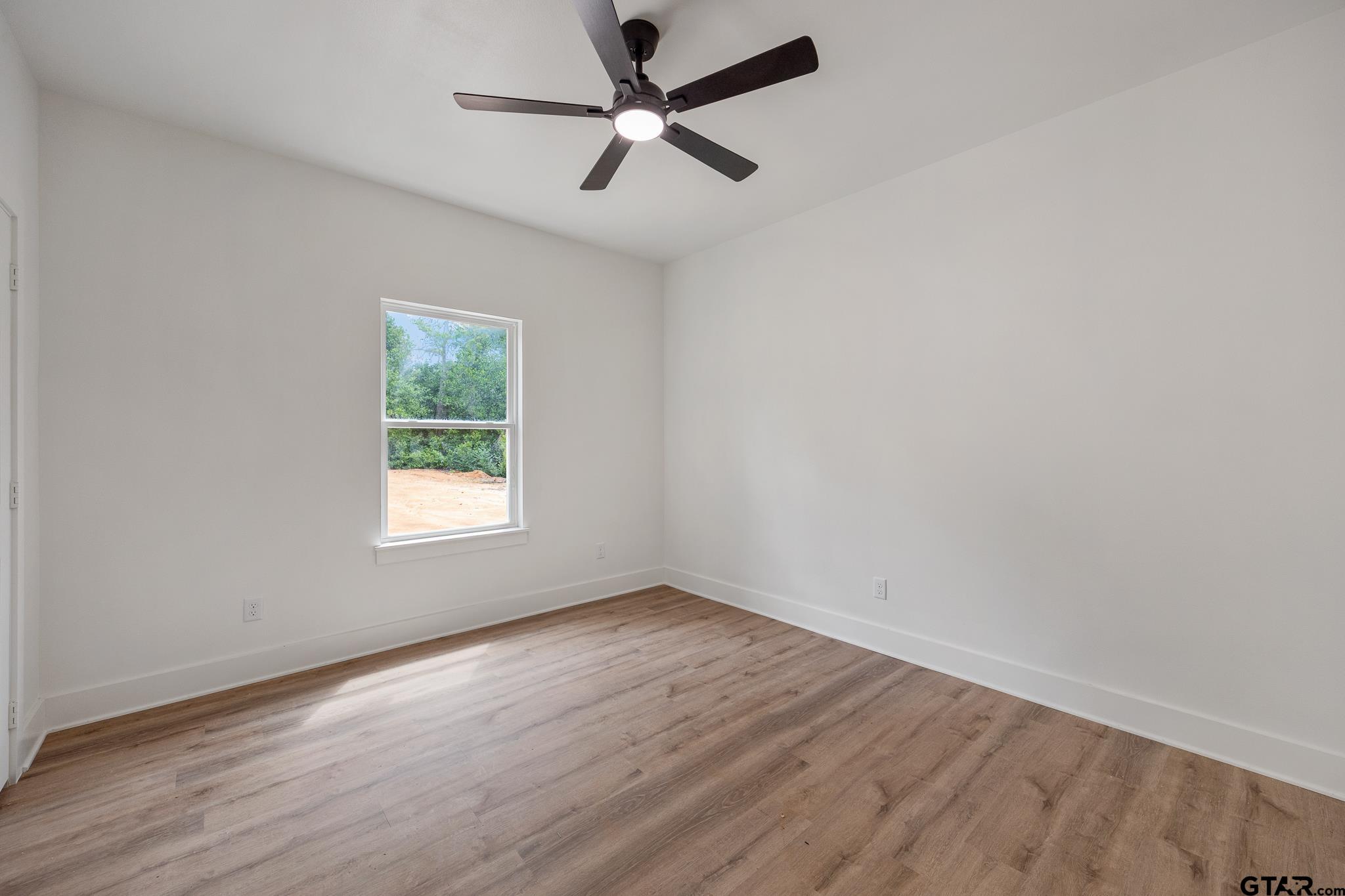 726 Boyd Avenue Tyler, TX 75701 - Photo 21 of 28 an empty room with wooden floor ceiling fan and windows