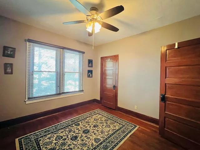 a view of an empty room with a window and wooden floor