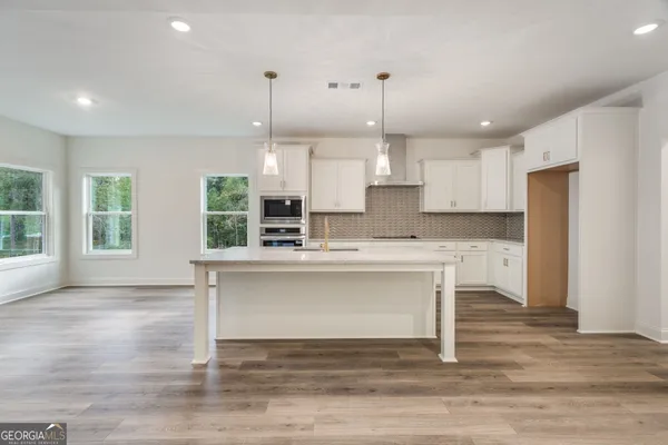 a view of kitchen with kitchen island wooden floor center island and stainless steel appliances