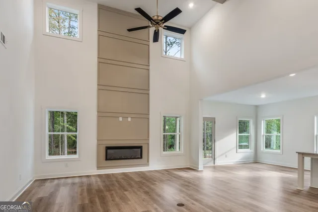 a view of an empty room and kitchen with wooden floor and a fireplace