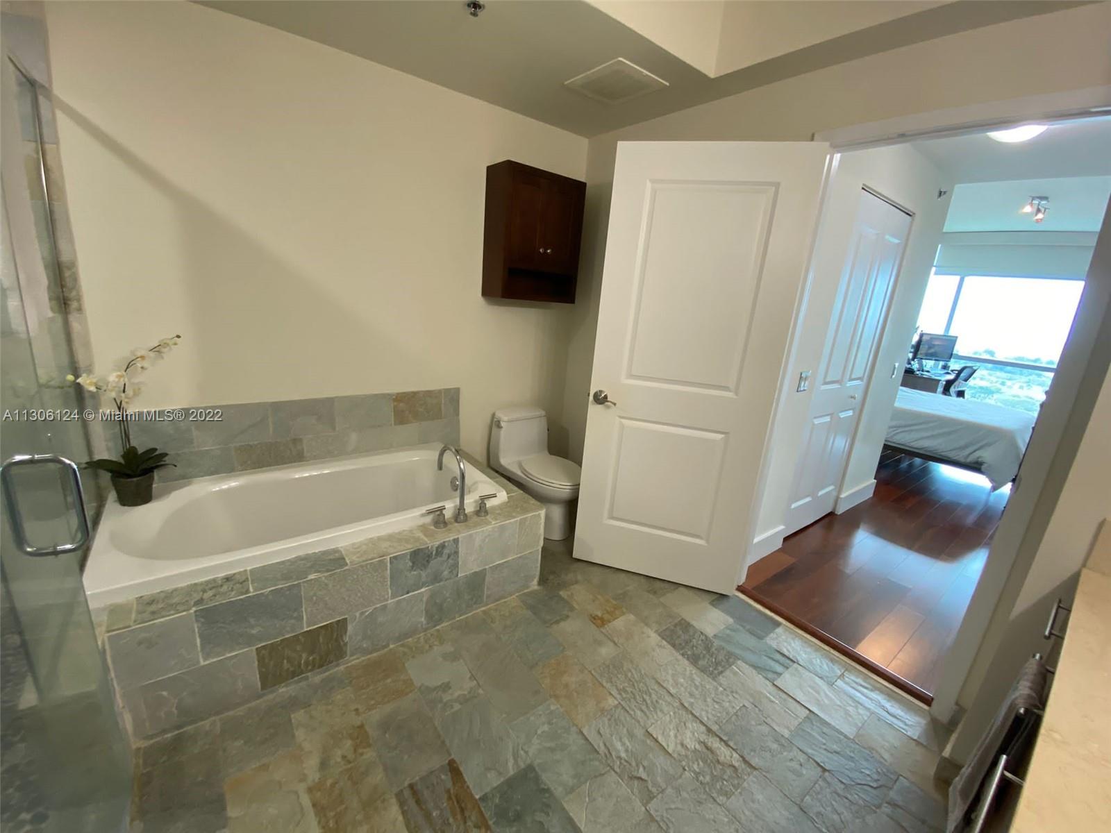 2681 North Flamingo Road, Unit 1905S Sunrise, FL 33323 - Photo 19 of 24 a bathroom with a tub a toilet a sink and a mirror