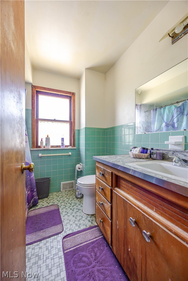 3825 Mayfield Road Cleveland Heights, OH 44121 - Photo 21 of 27 Bathroom featuring a single window with wood trim, a wood-finish vanity with drawer storage, a single basin sink, and a wall-mounted mirror