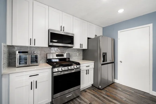 a kitchen with stainless steel appliances a stove a microwave and white cabinets