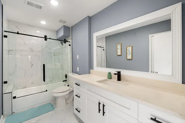 a bathroom with a double vanity sink toilet mirror and shower