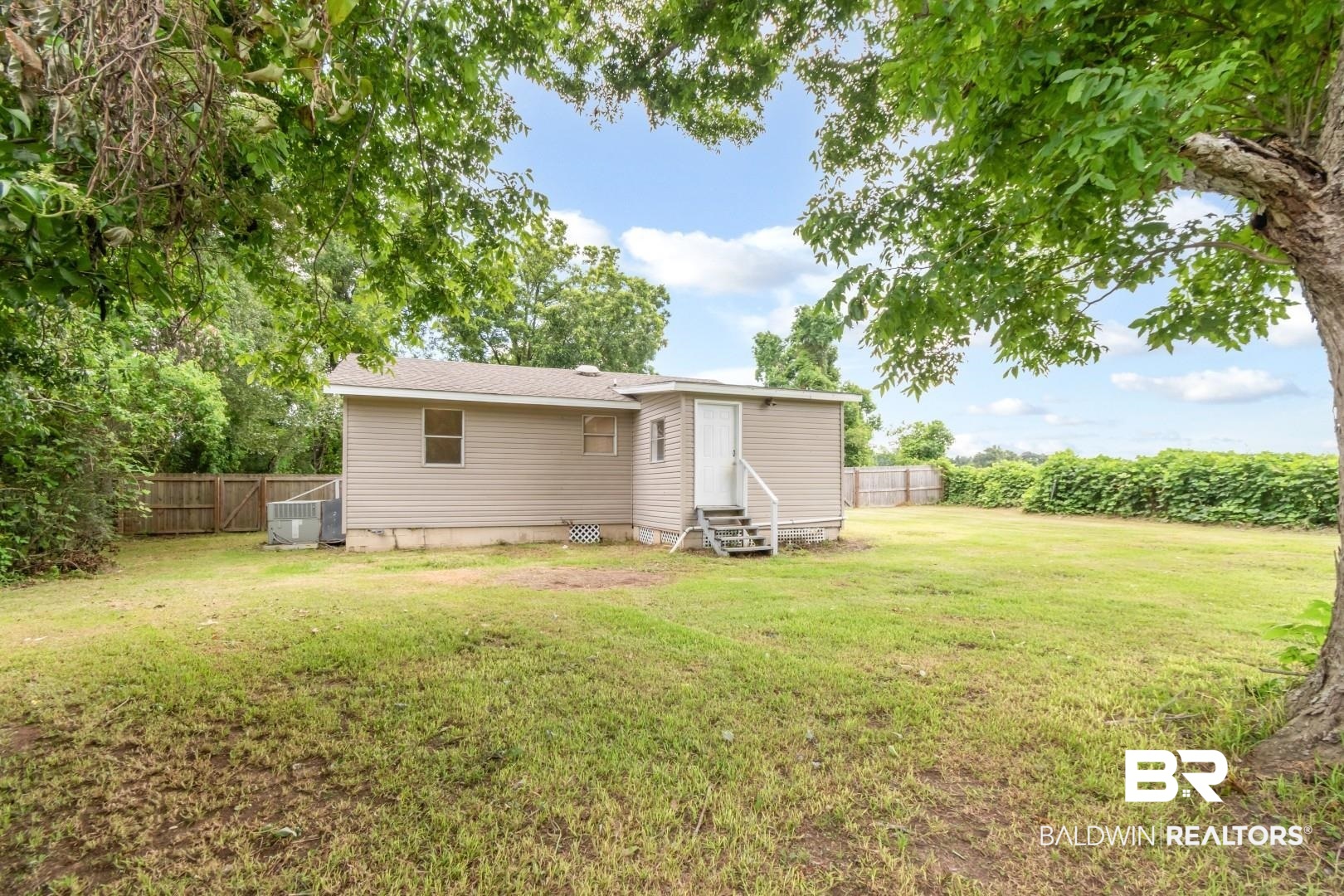 2905A McFarland Road, Unit F Mobile, AL 36695 - Photo 29 of 29 Expansive backyard featuring mature trees, a wooden privacy fence, and a single-story residence with horizontal siding